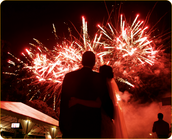 A couple is hugging in front of fireworks.