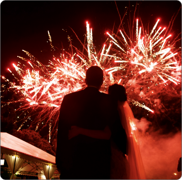 A couple is hugging in front of fireworks.